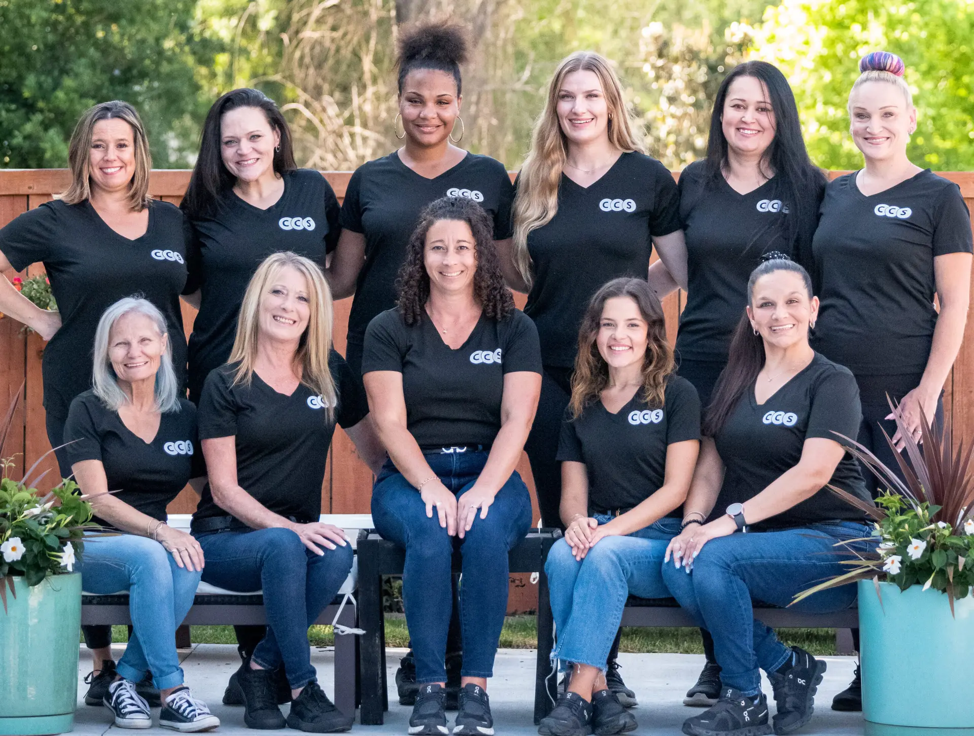 An image showing a group of women in matching black shirts posing together, with a 'Best Cleaning Service' banner in the background.